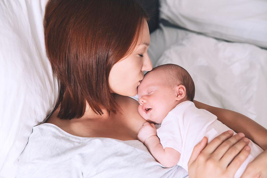 Woman and sleeping baby enjoying a peaceful moment in bed.